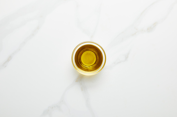 Vista superior del aceite de oliva en un recipiente de vidrio sobre fondo de mármol
 - Foto, imagen