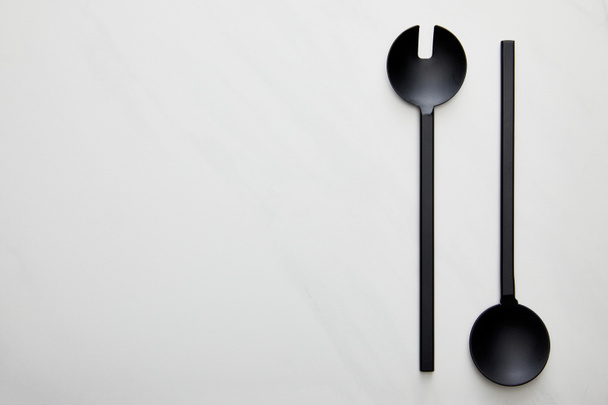 Top view of black ladle and spoon on marble background - Foto, afbeelding
