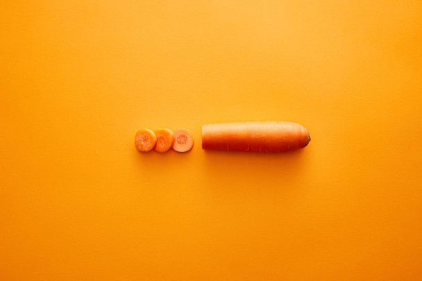 Vista superior de la zanahoria con rodajas sobre fondo naranja
 - Foto, imagen