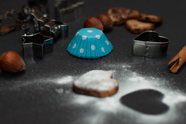 Úhlový pohled na cookies a pečicí zařízení na černém pozadí - Fotografie, Obrázek
