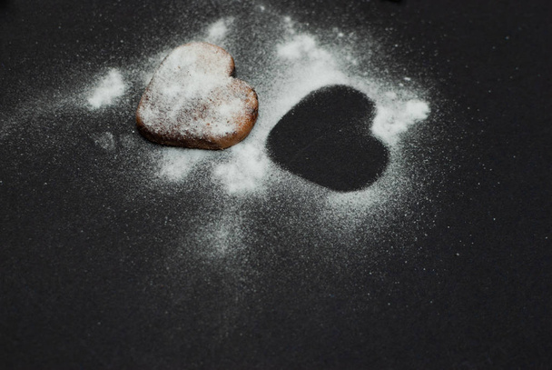 Vista angulada de um biscoito com açúcar em pó no fundo preto
 - Foto, Imagem