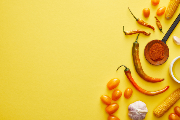 Bovenaanzicht van biologische groenten met chili kruiden en olijfolie op gele achtergrond - Foto, afbeelding