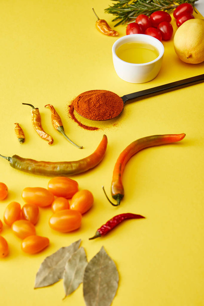 Chili peppers with spices and ripe vegetables on yellow background - Foto, Bild