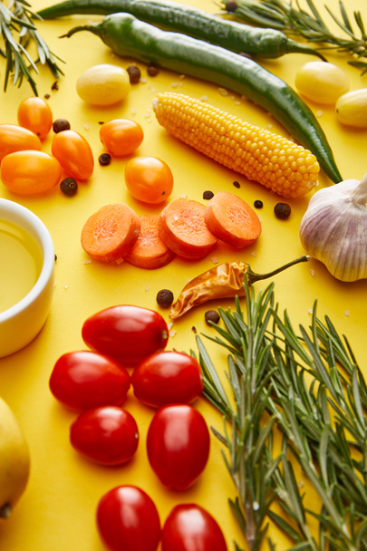 Fresh rosemary with vegetables, spices and olive oil on yellow background - Photo, Image