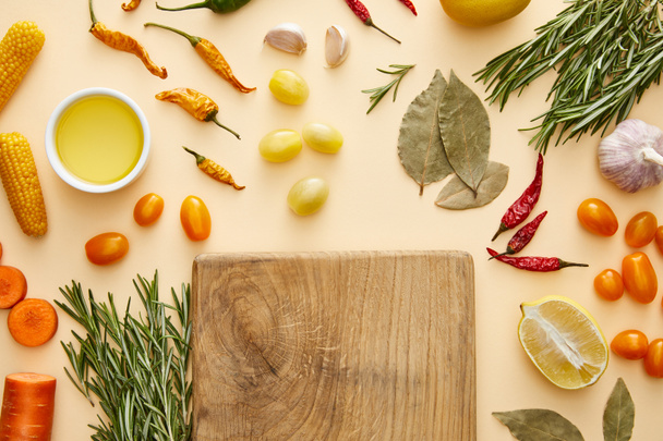 Top view of cutting board with fresh vegetables and rosemary on beige background - Foto, afbeelding