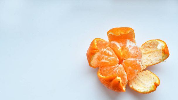 白い背景にみかんの皮をむいた。オレンジの果実と皮をむいた部分孤立した。オレンジの部分の山 - 写真・画像