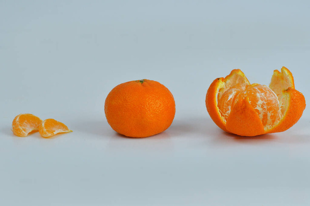очищенный мандарин на белом фоне. Оранжевые фрукты и очищенный сегмент изолированы. Куча оранжевых сегментов
 - Фото, изображение