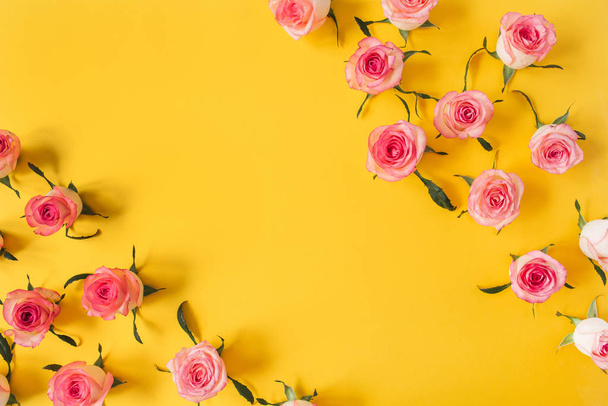 Flat lay frame border with blank copy space mockup made of pink rose flower buds on yellow background. Top view floral concept. - Photo, Image