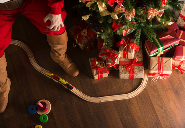 Unrecognizable Santa Claus playing with wooden railroad near Chr - Фото, зображення