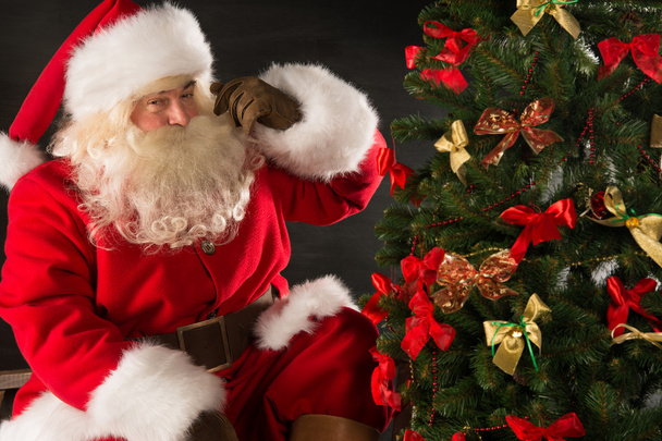 Santa Claus standing near Christmas tree in dark room - Valokuva, kuva
