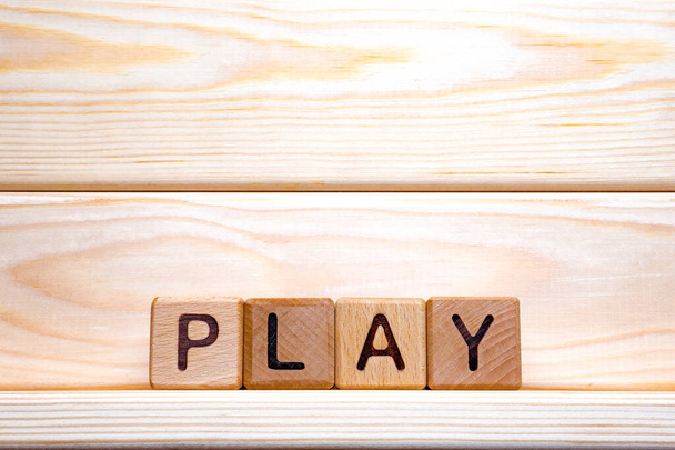 Wooden cubes form the word play. Word play formed with wooden cubes. Toy cubes made of wood on wooden background. Concept of play. Play sign background. Word formation - Photo, Image
