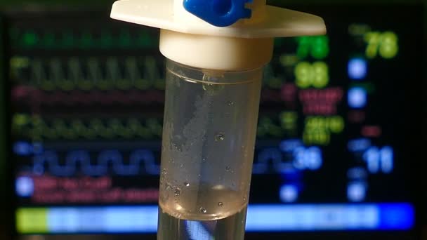 I.V. Gotejamento de solução salina intravenosa com o fundo do Monitor de Pacientes na sala de emergência, close-up
 - Filmagem, Vídeo