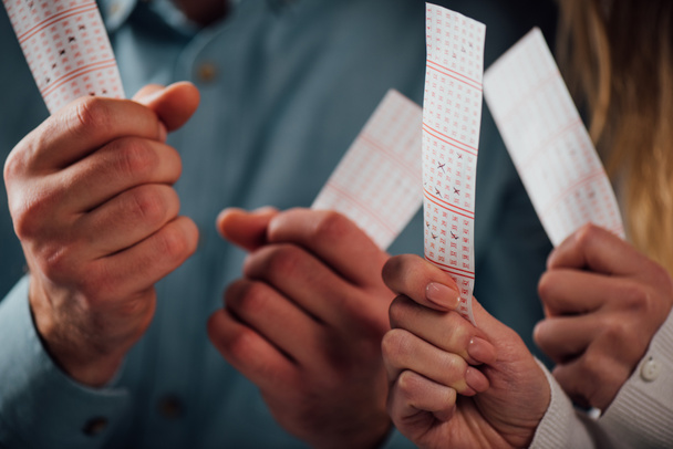 обрізаний вид чоловіка і жінки, що тримає лотерейні квитки під час очікування результатів лотереї
 - Фото, зображення