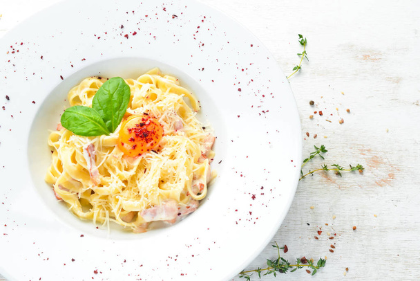 Traditional Italian pasta dish, spaghetti carbonara with yolk, parmesan cheese on a plate. Top view. Free copy space. - Photo, image
