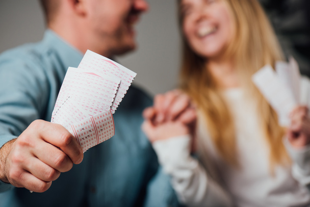 vista cortada de homem feliz e mulher de mãos dadas enquanto segurando bilhetes de loteria
 - Foto, Imagem