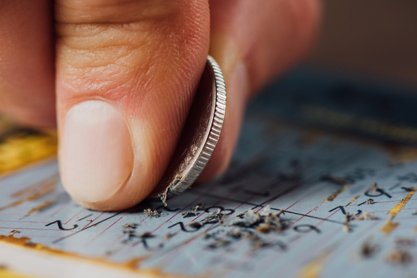 közeli kilátás ezüst érme kezében szerencsejátékos karcolás lottó kártya - Fotó, kép
