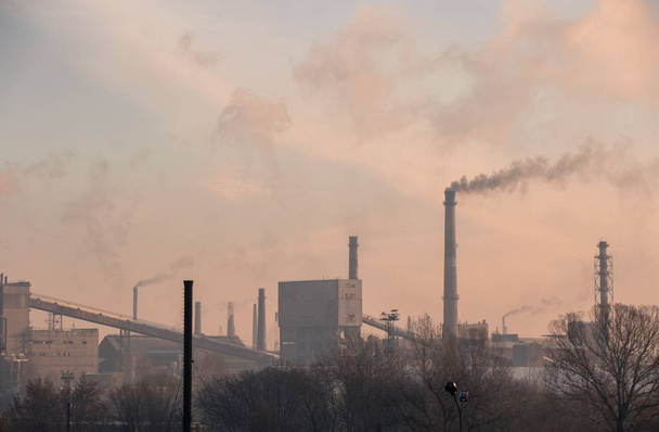 Silhouette of a metallurgy plant with smokestacks releasing fume  - 写真・画像