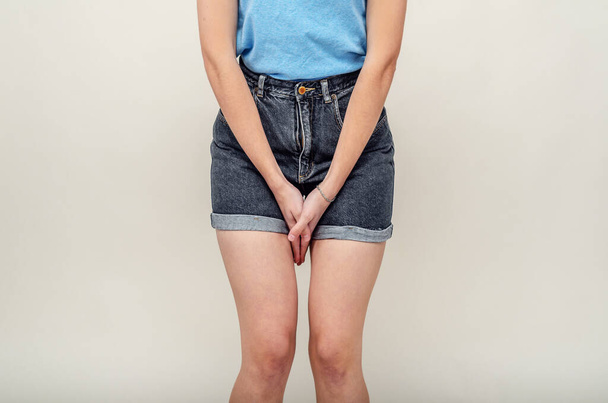 Young woman in shorts and a bra is experiencing pain in the uterus, pressed her hands to the lower abdomen. Medical concept. Gynecological problems. - Фото, зображення