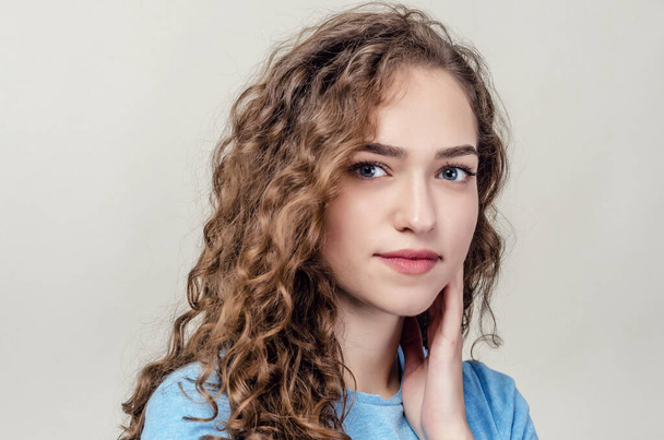 Portrait of beautiful young girl, close-up. Curly hair. Playing hair. Seductive smile - Photo, Image