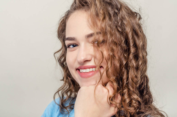 Portrait of beautiful young girl, close-up. Curly hair. Playing hair. Seductive smile - Photo, Image