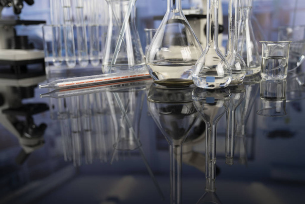 Laboratório de ciências. Beakers, tubos de ensaio e microscópio em mesa de vidro no laboratório
. - Foto, Imagem