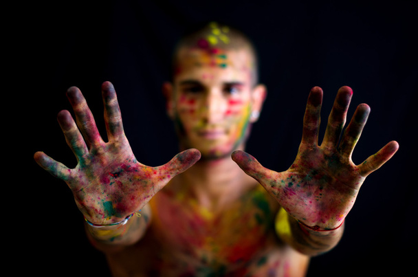 Handsome young man showing hands with skin all painted with colors - Foto, immagini