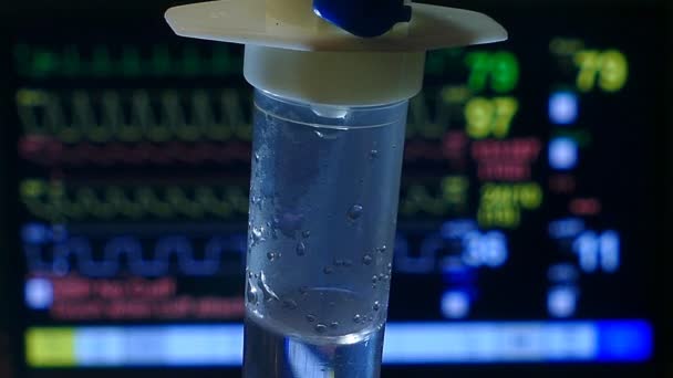 I.V. Gotejamento de solução salina intravenosa com o fundo do Monitor de Pacientes na sala de emergência, close-up
 - Filmagem, Vídeo