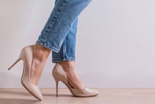 Womans feet close-up wearing high heel shoes and jeans - Φωτογραφία, εικόνα