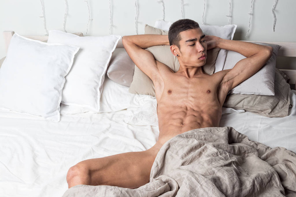 Young handsome man rest in bed. Sexy naked guy is resting - Foto, afbeelding
