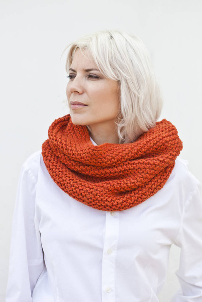 Pretty young woman in warm orange wool knitted snood scarf. - Foto, Imagem