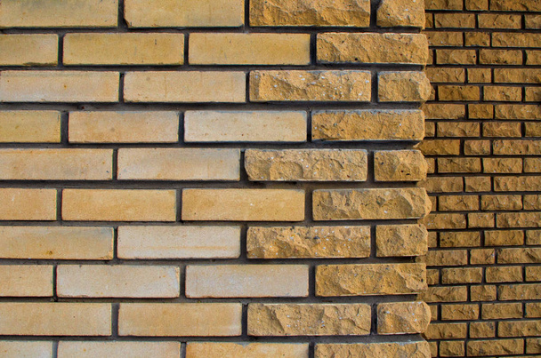 Fragment of the facade of a yellow brick house. There is a decorative brick trim with a chipped edge. In the background there is a dark part of the wall. Background. Texture. - Valokuva, kuva