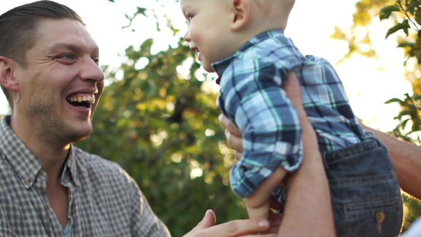 Abuelo, hijo y nieto se divierten en el huerto de manzanas al atardecer. Deslumbramiento solar. Familia feliz, tres generaciones, día del padre
 - Imágenes, Vídeo