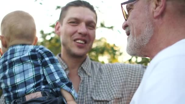 junger Mann mit kleinem Sohn und älterem Vater im Park bei einem Abendspaziergang. glückliche Familie, drei Generationen von Männern - Filmmaterial, Video