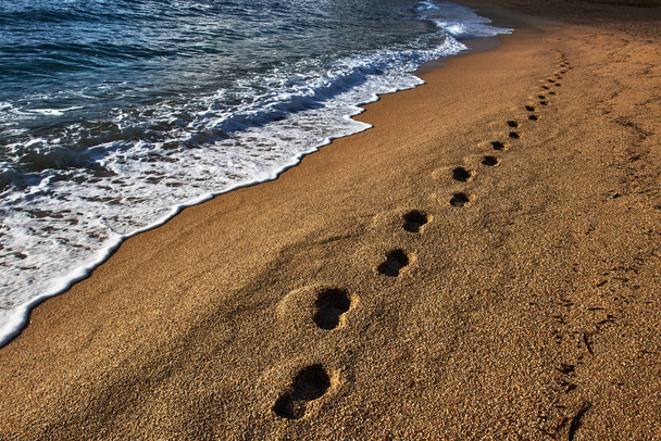 Lábnyomok a homokban a partvonal mentén - Fotó, kép