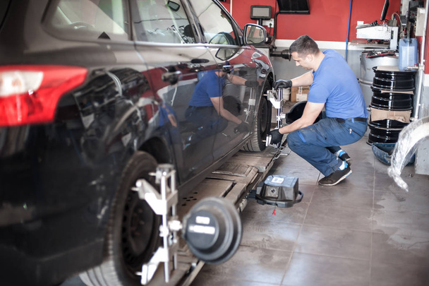 Wheel alignment. Car mechanic installing sensor during suspensio - Photo, Image