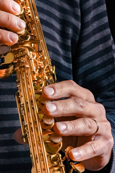 soprano saxophone in the hands of a guy on a black background - Foto, immagini