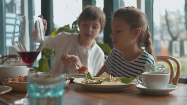 母と息子は皿からチーズを取り女の子はピザを食べる - 映像、動画