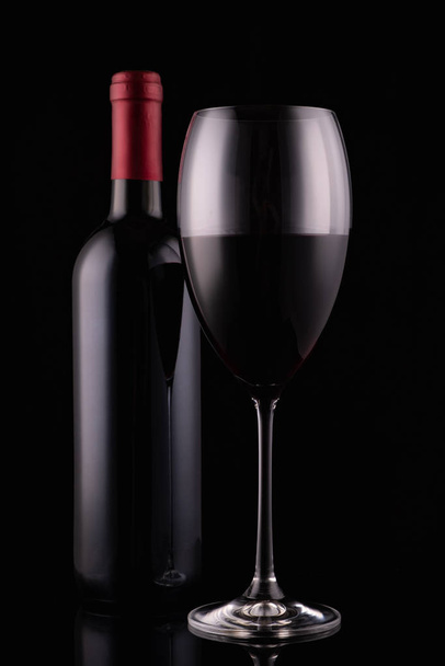 Elegant red wine glass and black wine bottle on black background - Foto, Imagem
