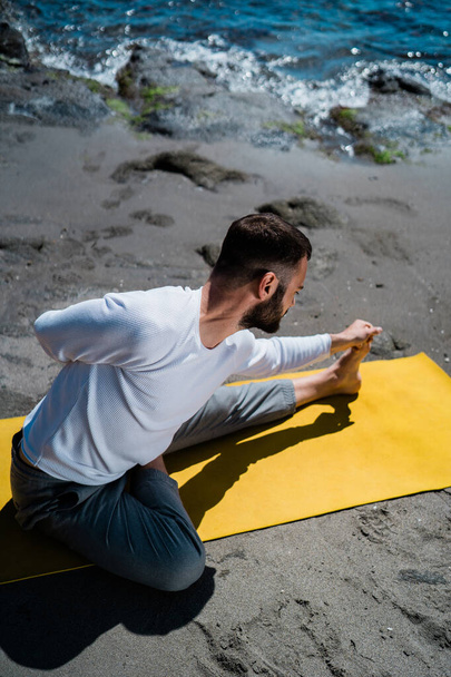 Caucasian Man doing a Yoga Practice on a natural beach - 写真・画像