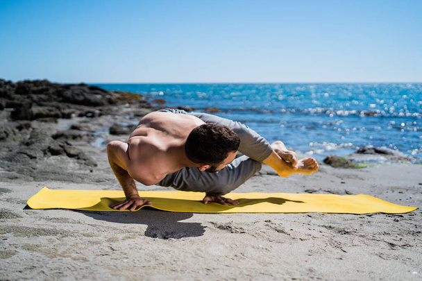 Muscular, Fit Man Doing Yoga Stretches Outside on a Beach In Morning Sunlight. - Foto, immagini