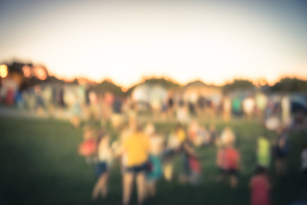 abstrakte verschwommene große gruppe unterschiedlicher menschen besuchen sommerveranstaltung im urbanen park in der nähe von dallas, texas, amerika. Gruppe von Familienmitgliedern genießt öffentliches Fest bei Sonnenuntergang mit Bokeh-Beleuchtung - Foto, Bild