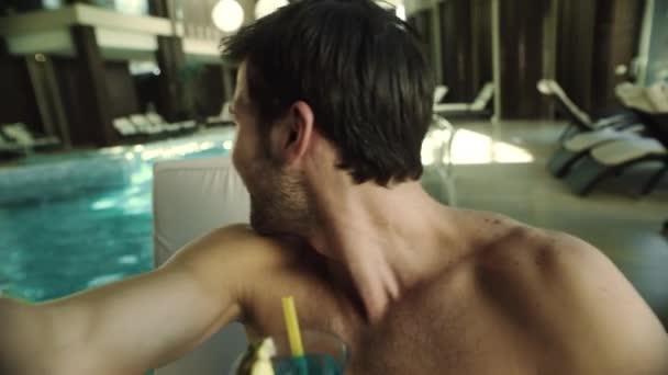 Primer plano del hombre bebiendo cóctel en la piscina del hotel. Feliz hombre grabación de vídeo - Metraje, vídeo