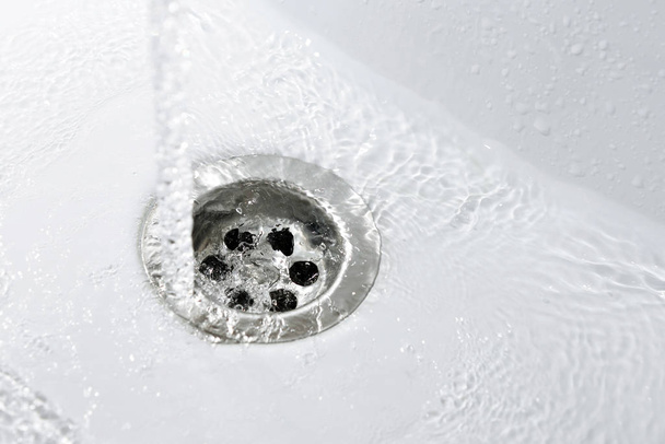 Вода тече в нову білу раковину у ванній
 - Фото, зображення