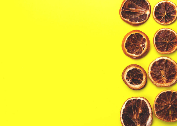 Slices of Dried oranges on yellow background. New Year or Christmas card. - Photo, Image
