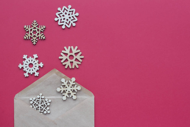 Envelope and wooden snowflakes on a red background. Top view winter copy space - Foto, Imagen