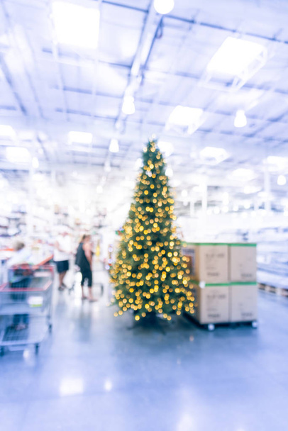 Toptan mağazabulanık büyük Noel ağaçları dekorasyon. Çelenkler ve bokeh ışıkları dizeleri yapay Noel ağacı çevreleyen. Abd'de satış için görüntülenen Xmas süslemeleri. Müşteri alışverişi - Fotoğraf, Görsel
