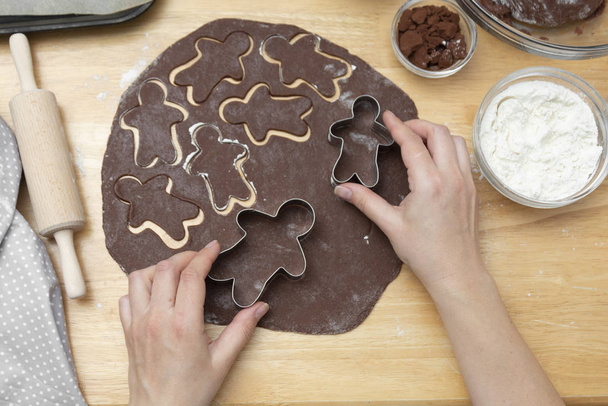 Women's hands cooking festive Christmas gingerbread cookies. Cooking chocolate cookies or dessert. - Foto, afbeelding