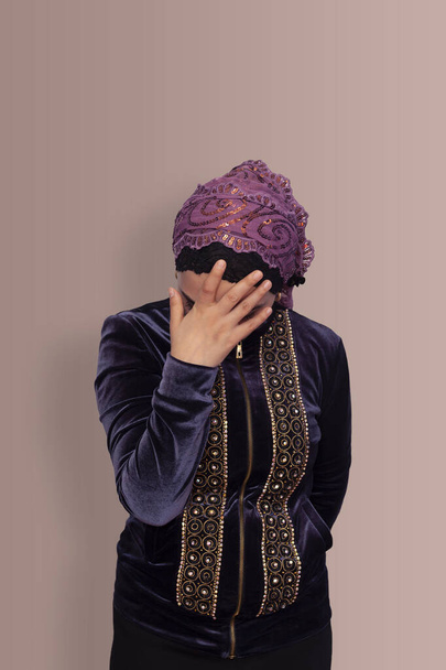 Turkse vrouw in traditionele kleding met een hoofddoek met hoofdpijn. Een jonge Iraanse vrouw die zich ongelukkig, gestrest en moe voelt. Moslim vrouw houdt haar hoofd vast - Foto, afbeelding