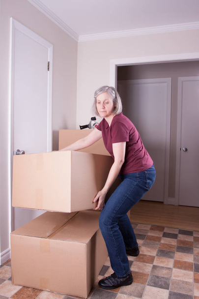 Dojrzałe siwe kobieta przygotowuje się do przejścia do innego domu stosy duże brązowe pudełka - Zdjęcie, obraz
