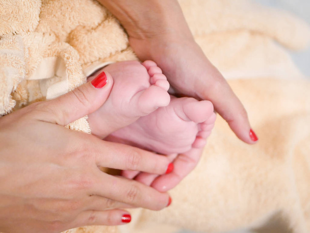 Gyerek lábak az anyák kezén. Fénykép egy újszülött lábáról. Anyám karjaiban. - Fotó, kép